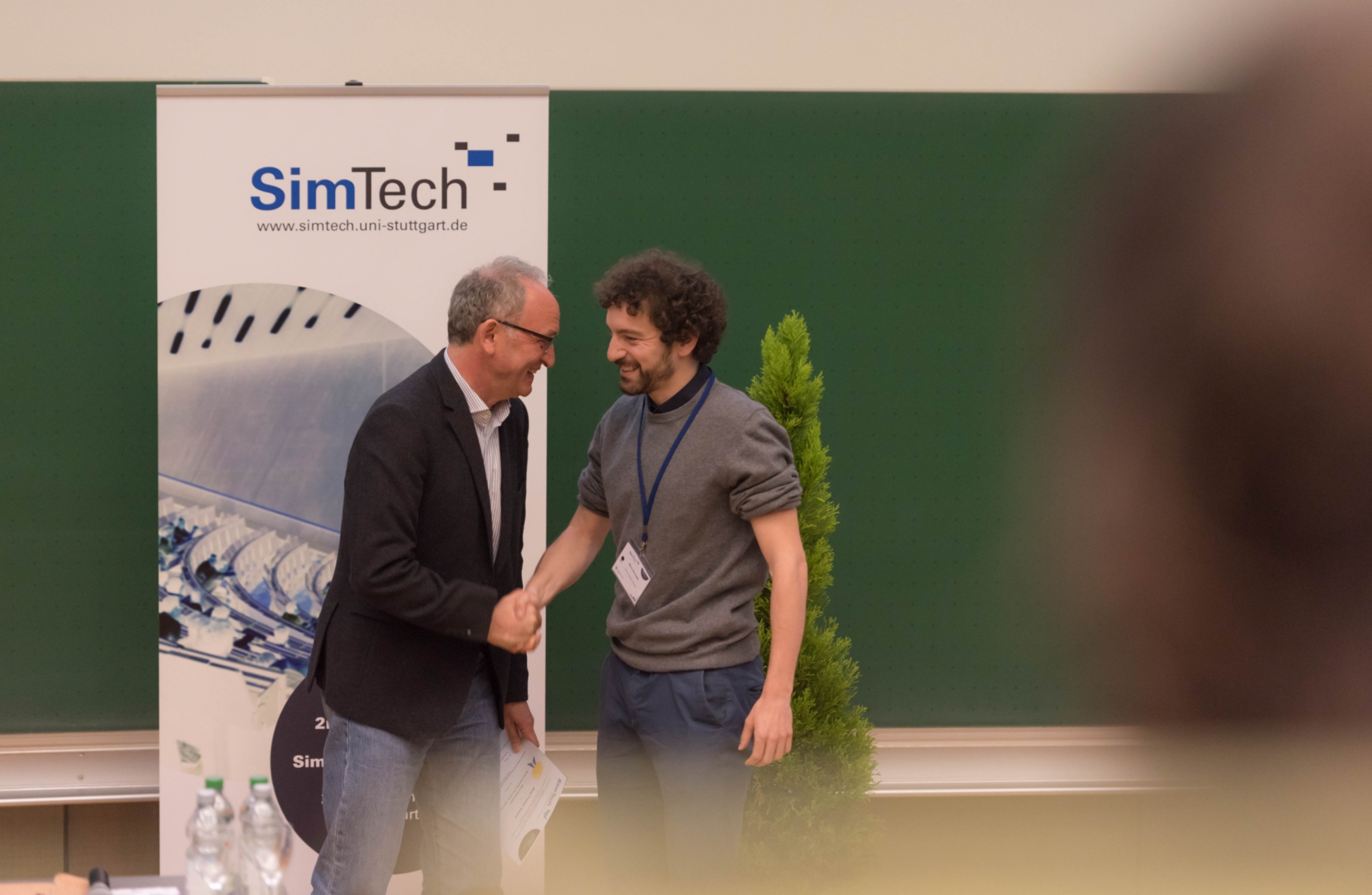 Prof. Rainer Helmig, Mitglied des Direktoriums von SimTech, gratuliert dem Gewinner des Best Poster Awards, Marco Salvalaglio von der TU Dresden.
